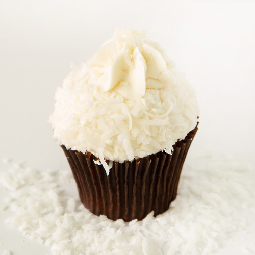 Coconut cake filled with coconut cream, topped with coconut buttercream rolled in fresh coconut